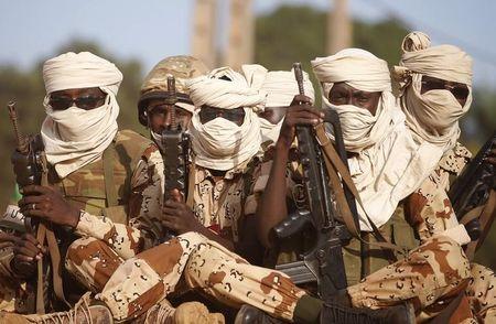 Chadian soldiers sit with guns on a vehicle as they drive in Bangui